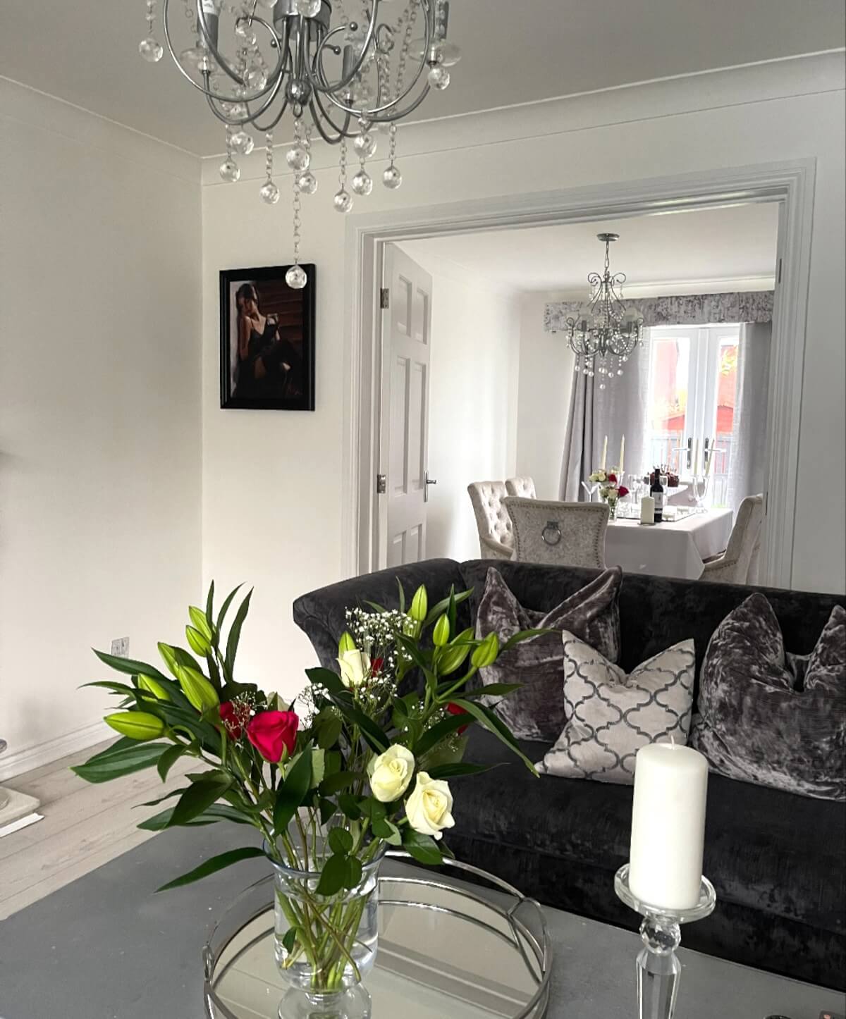 living-room-walls-painted-sunderland-foxglove-decor Living room with pale walls, a chandelier, a dark sofa and fresh flowers